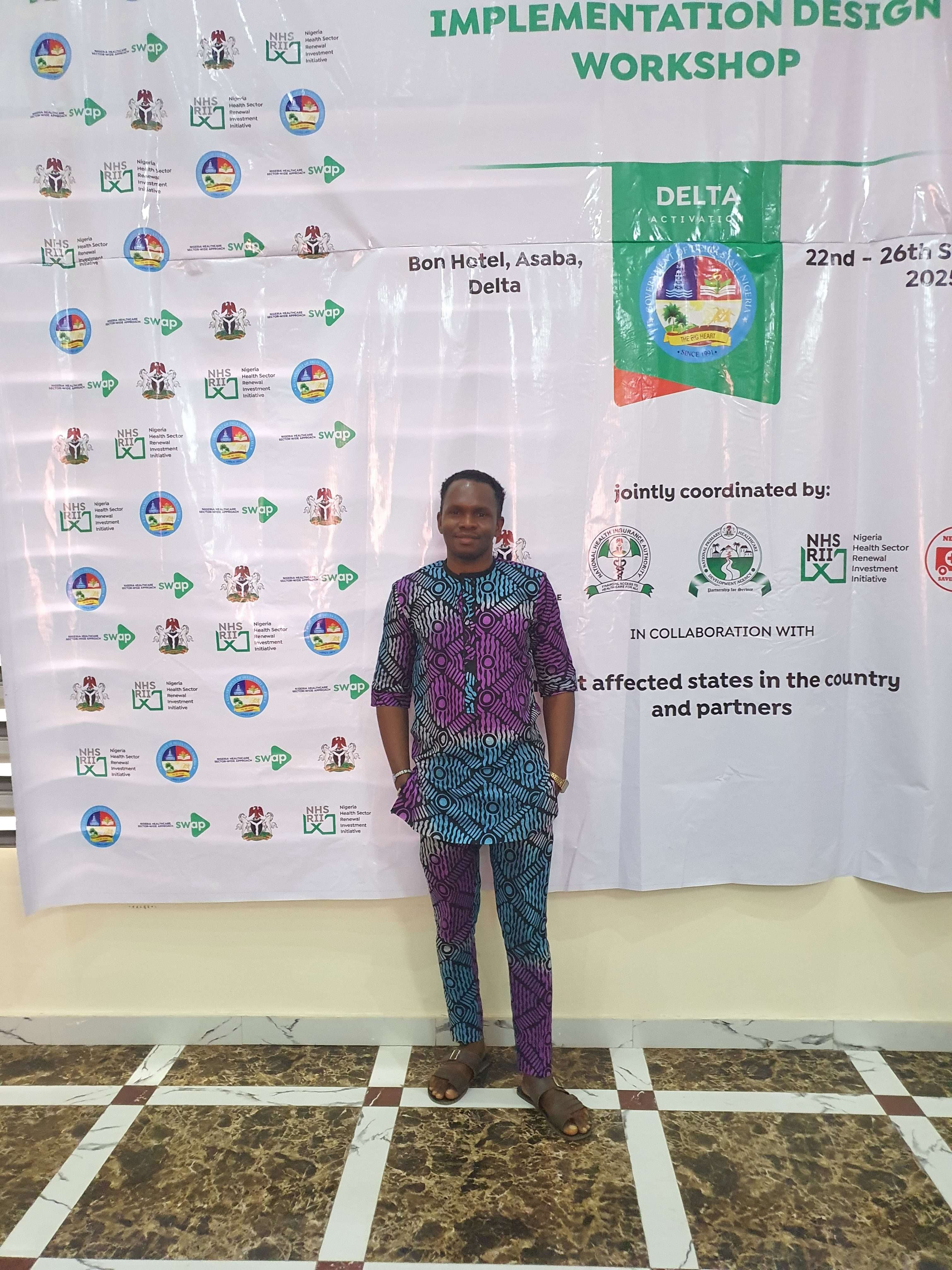Standing in front of the Implementation Design Workshop banner at Bon Hotel, Asaba